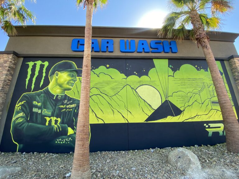 A terrible art mural of a green Riley Herbst in his racing uniform and the monster logo