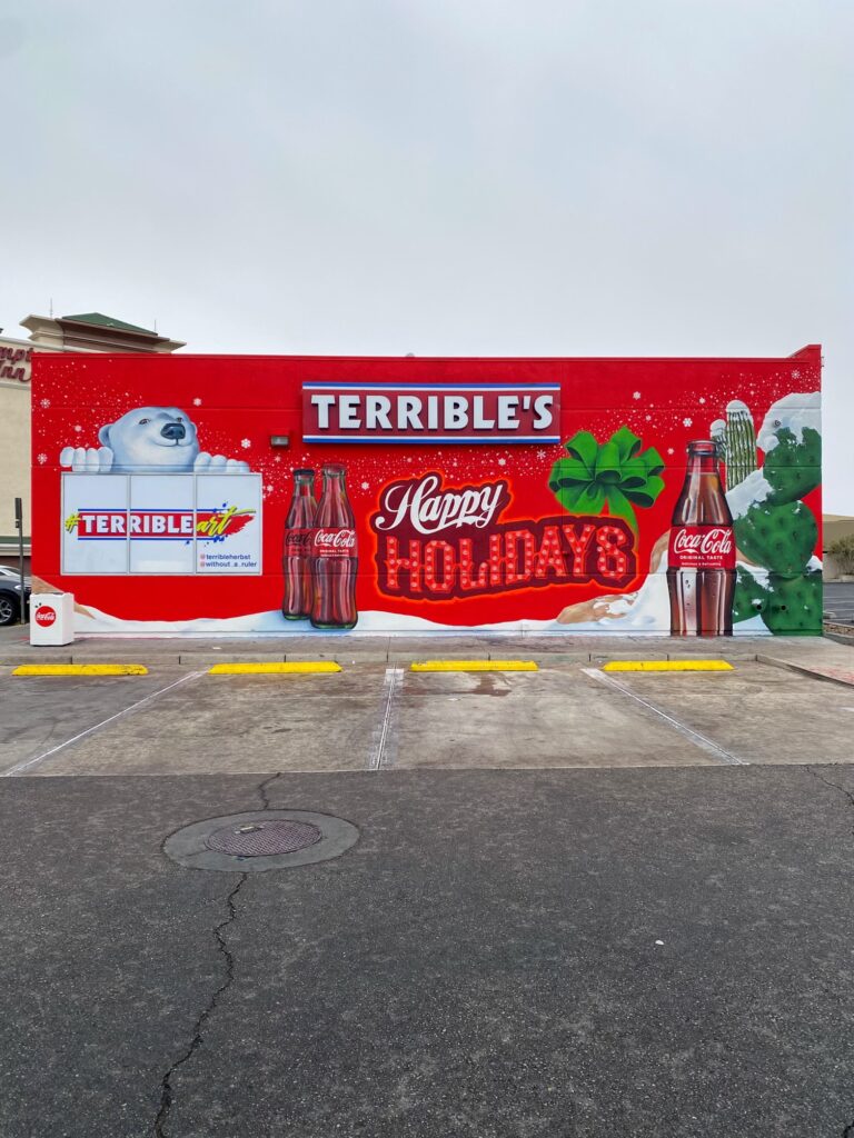 a terrible art mural that says happy holidays and has coke bottles and a polar bear